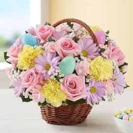 Basket of pink roses and pastel daisies with colorful eggs