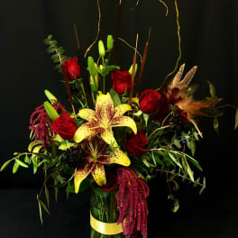 Tall bouquet of red roses and yellow lilies in a glass vase