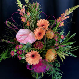 Colorful floral arrangement with pink anthurium and peach gerbera daisies in a glass vase