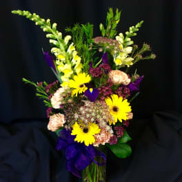 Mixed bouquet with yellow daisies, purple flowers, and peach carnations in a vase