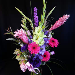 Tall mixed bouquet in a glass vase with pink, purple, and green blooms