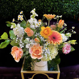 Mixed bouquet of peach, orange, white, and pink flowers in a vase