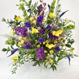 Large bouquet with yellow calla lilies, purple roses, and mixed greenery