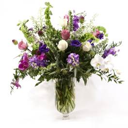 Mixed purple, pink, and white flowers in a clear glass vase