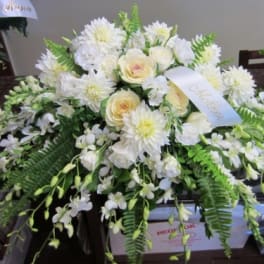 White floral casket spray with cream roses and daisies