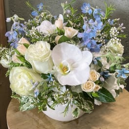White and pale blue floral arrangement in a white vase