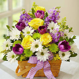 Basket arrangement of yellow roses, purple tulips, and white daisies