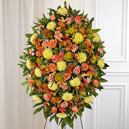 Standing spray of orange and yellow flowers on a black easel