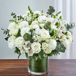 White roses and carnations in a glass vase with eucalyptus