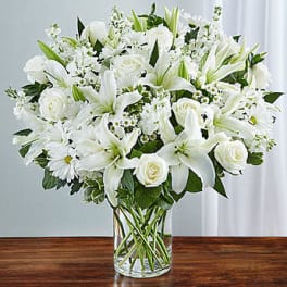 White lilies and roses arranged in a clear glass vase
