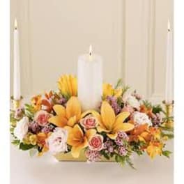 Floral centerpiece with white candles and yellow-orange blooms