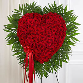 Heart-shaped red rose standing spray with a red ribbon