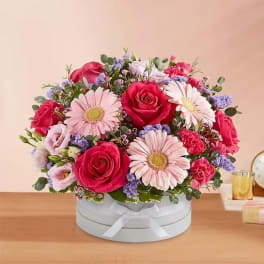 Pink and red roses with pale pink daisies in a round box