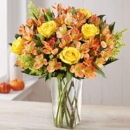 Yellow roses and orange alstroemeria in a clear glass vase