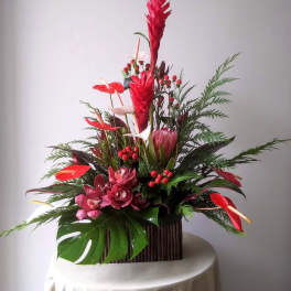 Tall tropical arrangement with red anthuriums and pink orchids in a rectangular container