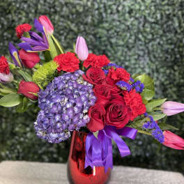 Bouquet of red roses, purple hydrangea, and tulips in a red vase