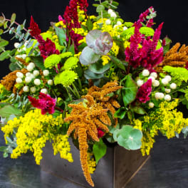 Colorful mixed flower arrangement in a dark square vase