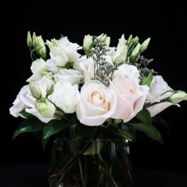 White roses and lisianthus arranged in a glass vase