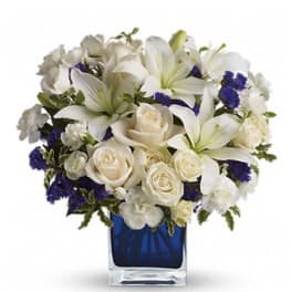 White lilies and roses arranged in a blue glass vase