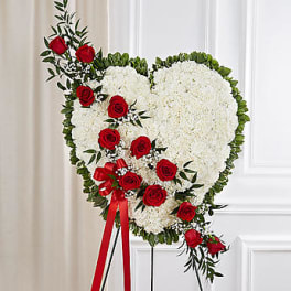 Heart-shaped white floral standing spray with red roses and ribbon