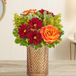 Bouquet of red daisies and orange roses in a textured gold vase