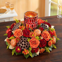 Autumn floral centerpiece with orange roses and a red candle holder