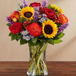 Bouquet of red roses and sunflowers in a clear glass vase