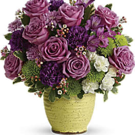Purple rose bouquet in a yellow ceramic vase
