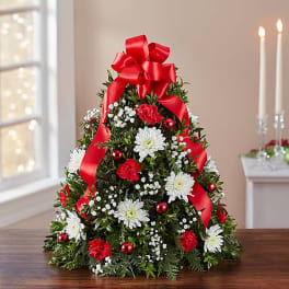 Christmas tree-shaped floral arrangement with red ribbon and white flowers