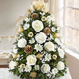 White rose and carnation Christmas tree arrangement with gold ribbon and pinecones