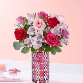 Bouquet of pink, red, and lavender roses in a patterned vase