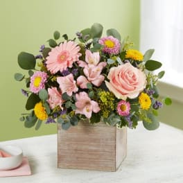 Pink and yellow mixed flower arrangement in a wooden box