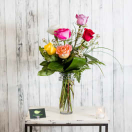 Mixed roses arranged in a clear glass vase with greenery
