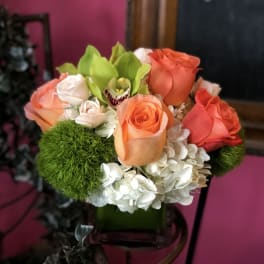 Bouquet of orange and coral roses with white hydrangeas in a vase