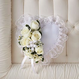 White rose bouquet with lace trim and ribbon on a cream tufted chair