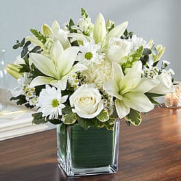 White lilies and roses arranged in a square glass vase