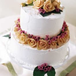 Three-tier white cake decorated with peach roses and pink flowers