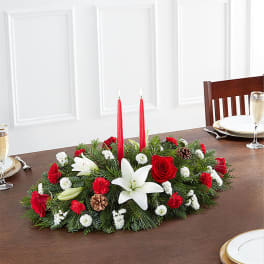 Holiday centerpiece with red candles, white lilies, and red roses
