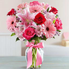 Pink and red mixed bouquet in a glass vase with a pink ribbon