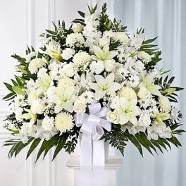White funeral spray with lilies and roses on a stand