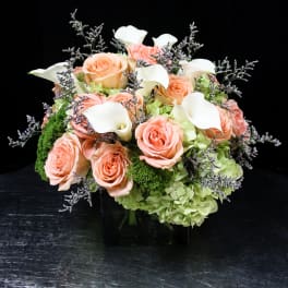 Peach roses and white calla lilies in a black vase