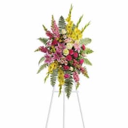 Tall mixed floral spray on a stand with pink, yellow, and white blooms