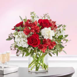 Red roses and white flowers arranged in a clear glass vase