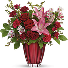 Red roses and pink lilies arranged in a red vase