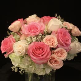 Pink and white roses arranged in a clear glass vase