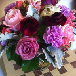 Mixed bouquet of roses, carnations, and daisies in a glass vase