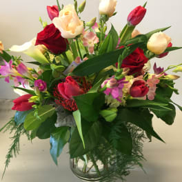 Mixed bouquet of roses, tulips, and orchids in a glass vase