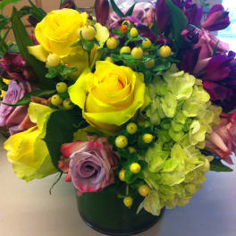 Bouquet of yellow roses, purple flowers, and green hydrangeas in a vase