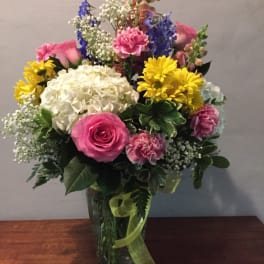 Mixed bouquet in a glass vase with pink roses, white hydrangea, and yellow daisies