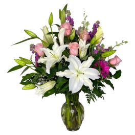 White lilies and pink roses arranged in a glass vase